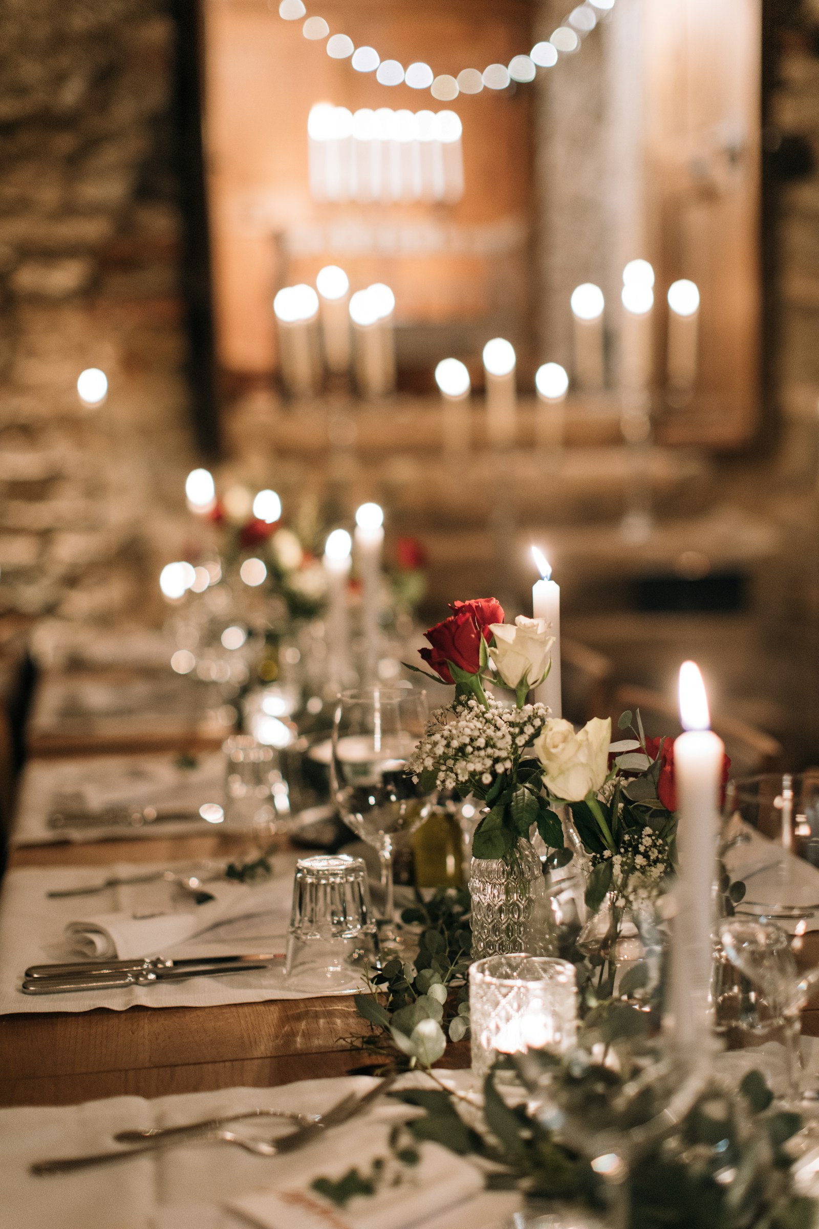 Mesa larga de banquete decorada con flores y velas
