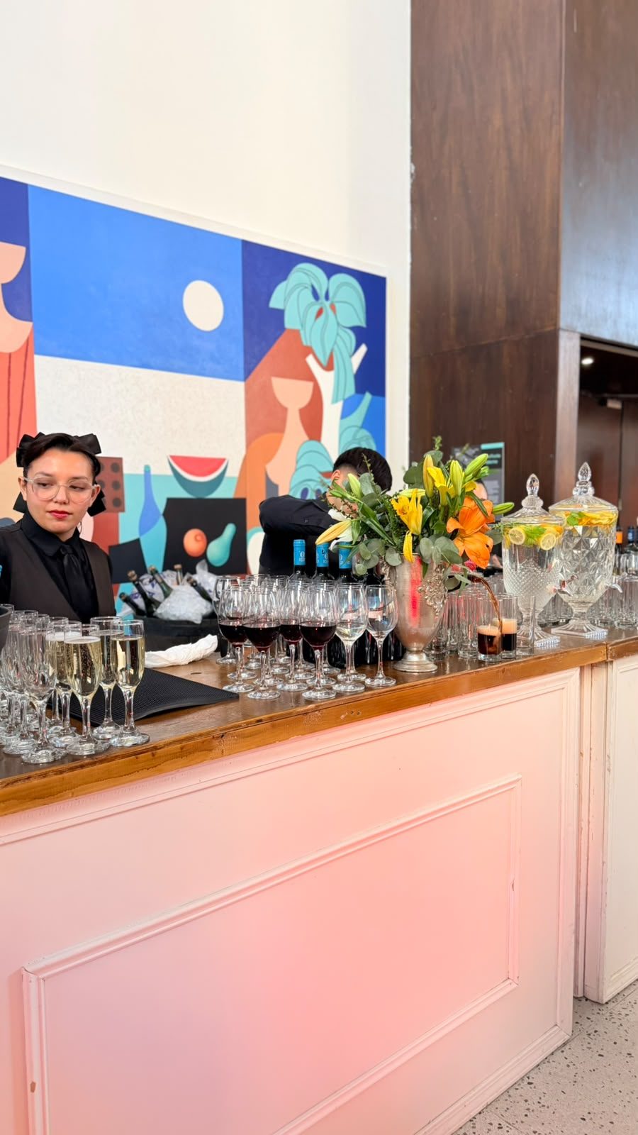 Barra de coctelería con copas y flores amarillas