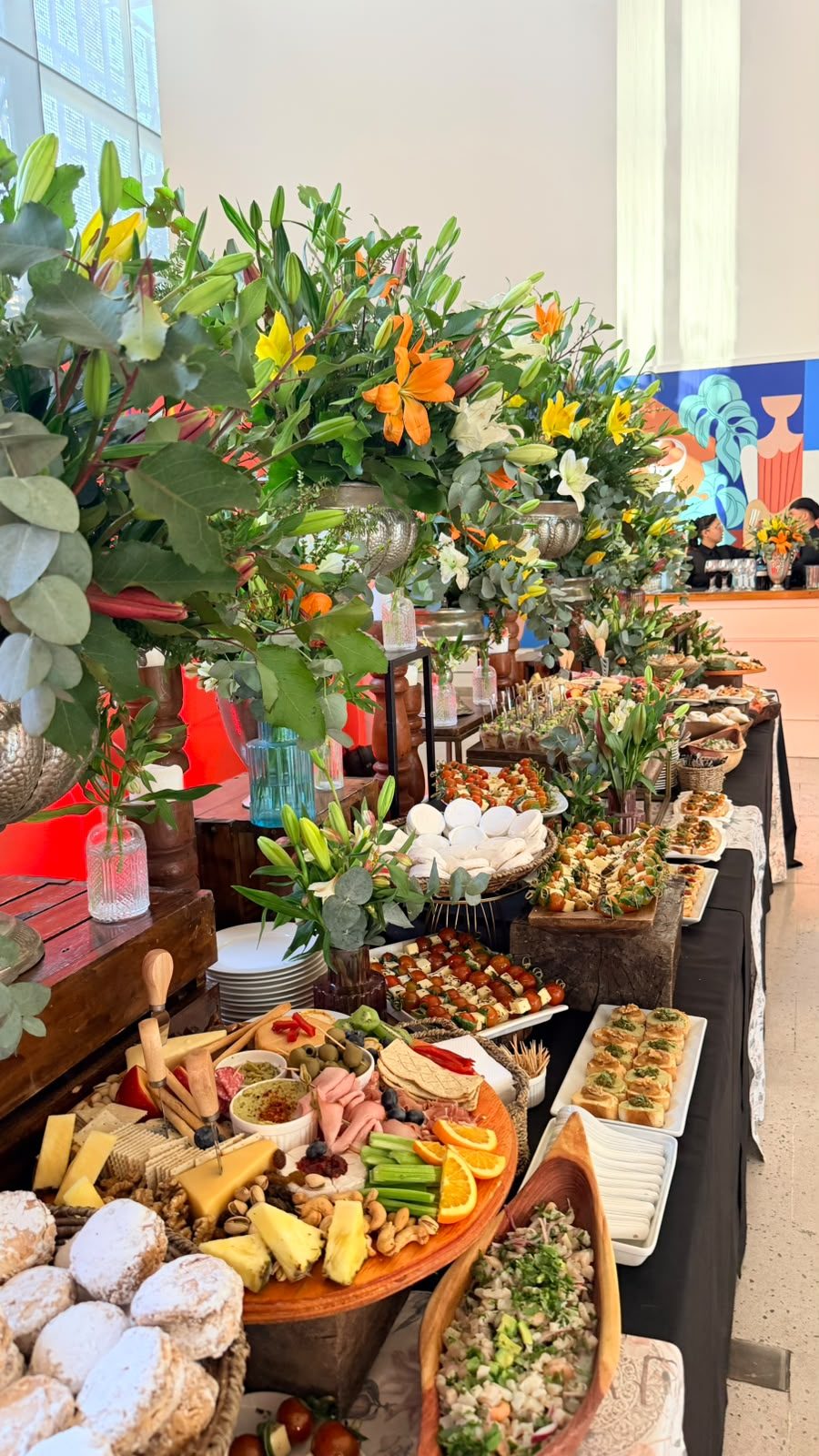 Buffet con tablas de quesos y arreglos de lirios