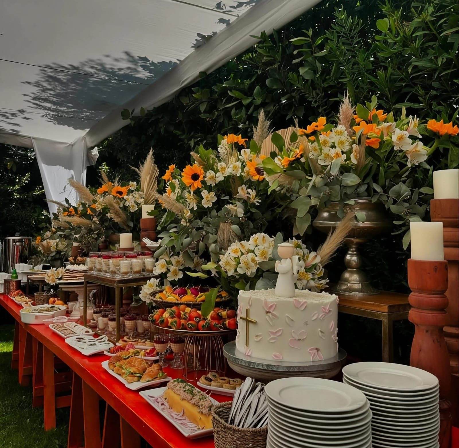 Mesa de buffet bajo carpa, ambientada con flores